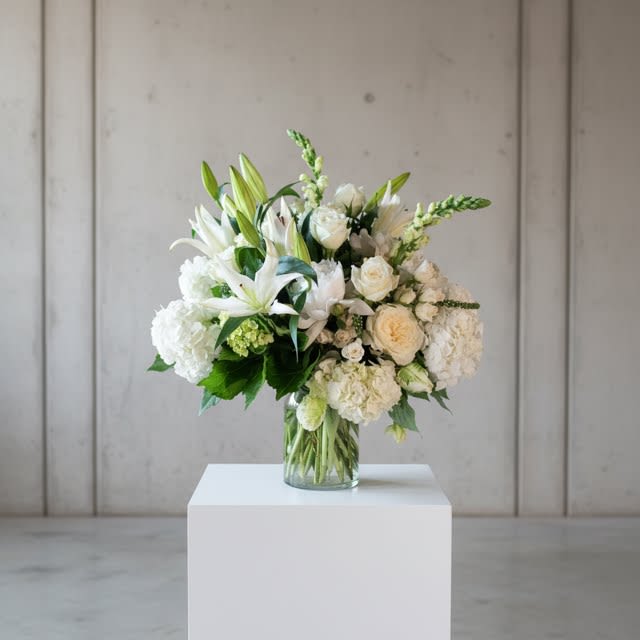 Belle Meade - Lush gathering of premium flowers.. all in luxurious whites, cream and greens.  Blooms like mounded hydrangea, fragrant oriental lilies, antique spray roses, Eskimo roses, snapdragons and more.  All placed in a simple clear glass vase to show off their elegant displays.