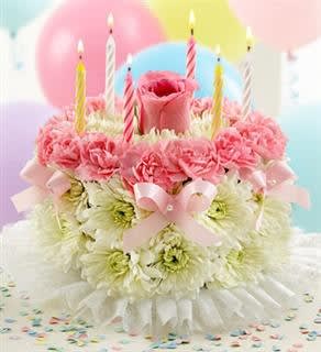 Pink and white flower arrangement topped with candles and balloons