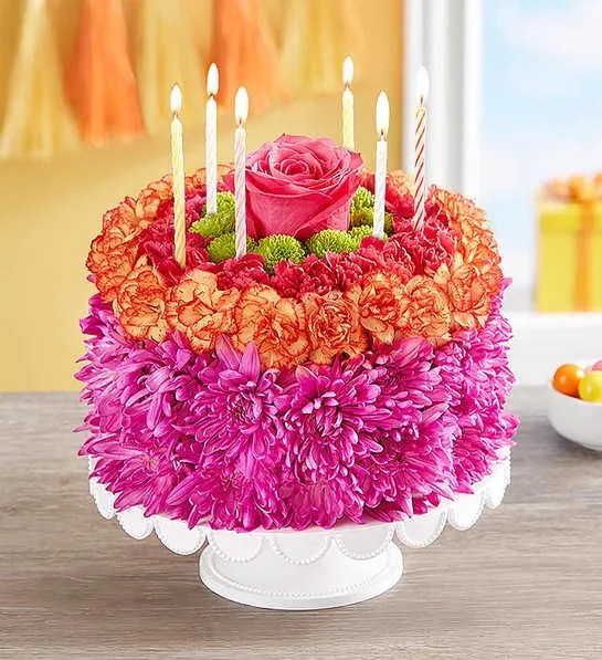 Round floral cake with candles and a pink rose on top