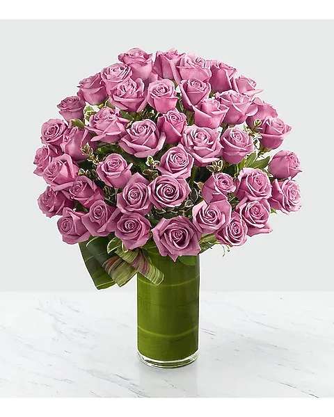 Pink roses arranged in a tall glass vase with a ribbon