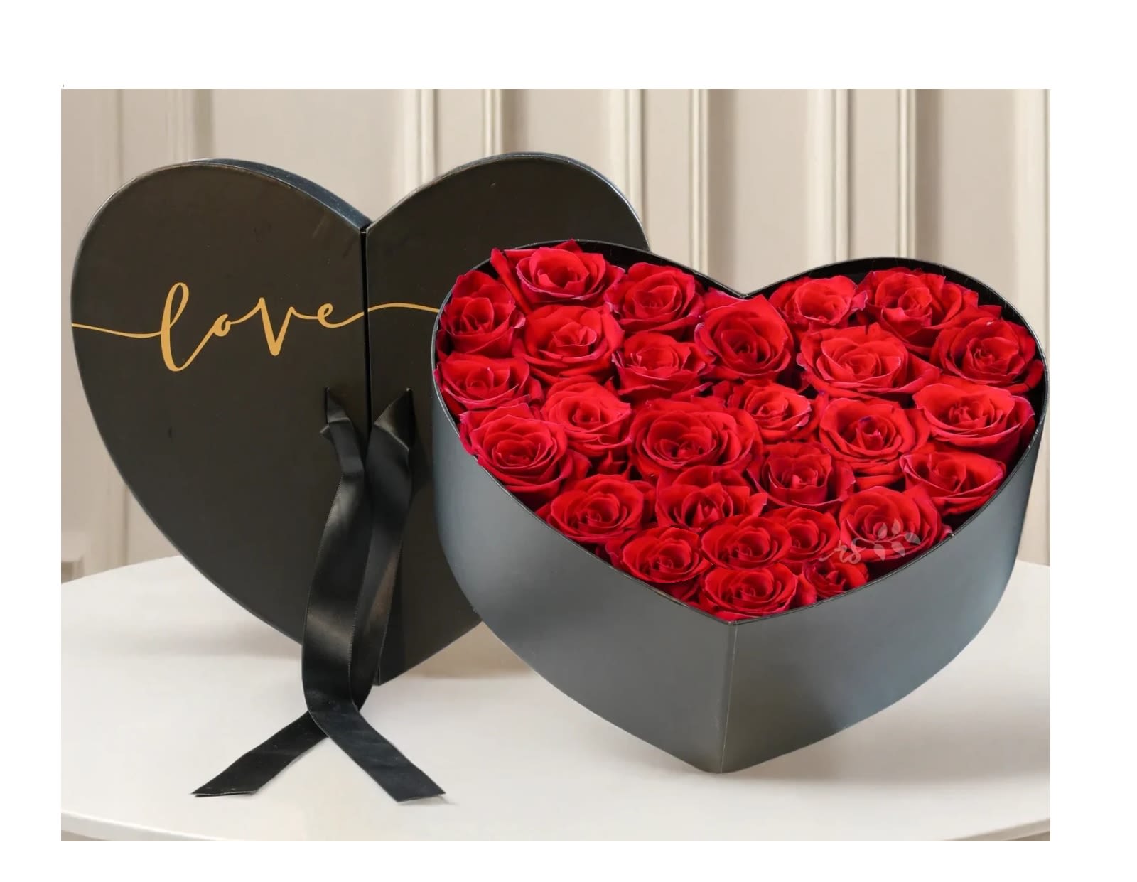 Heart-shaped box filled with red roses and a black ribbon