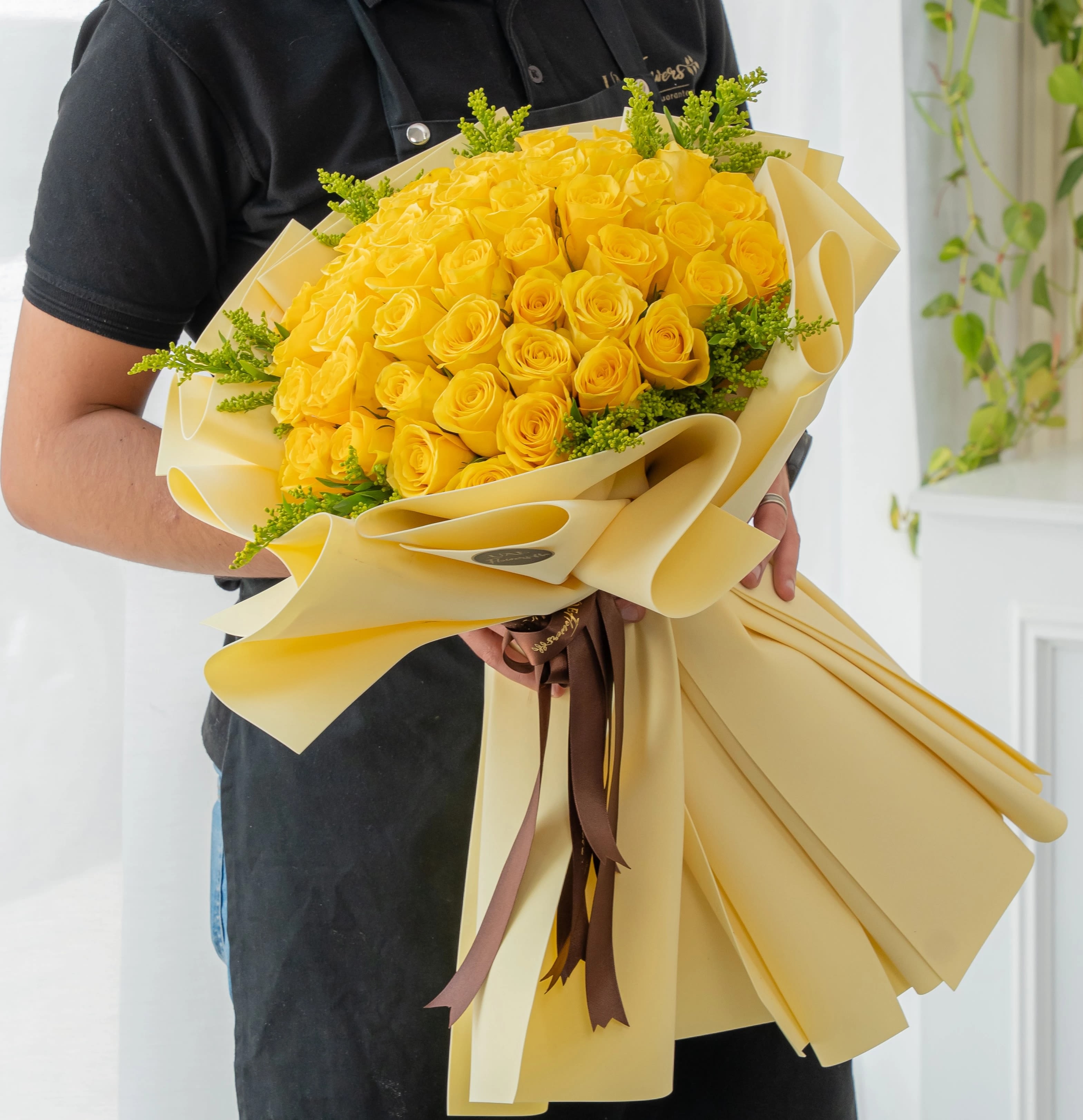 Bouquet of yellow roses wrapped in cream paper with brown ribbons