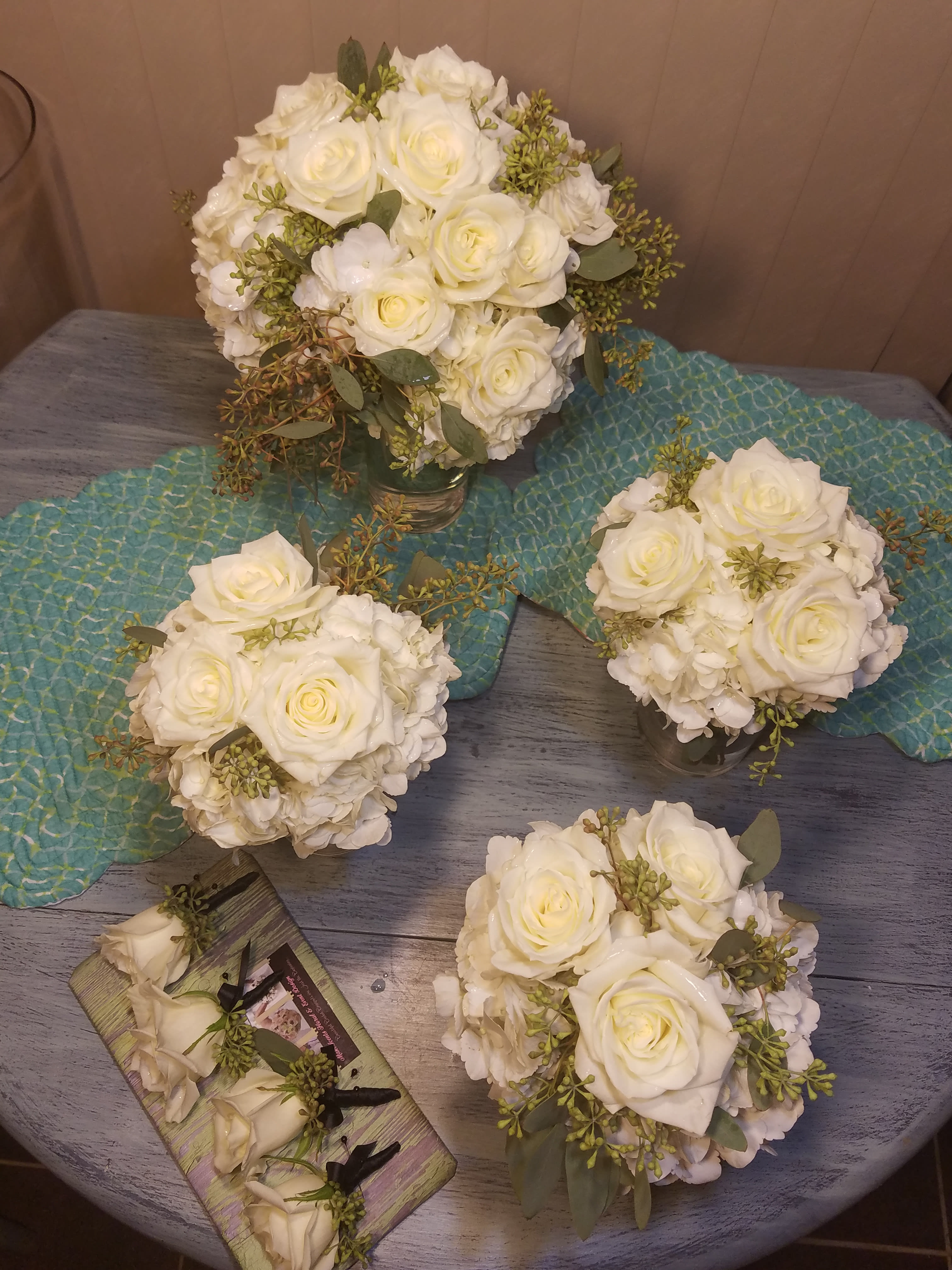 White rose bouquets with hydrangea and greenery on a table
