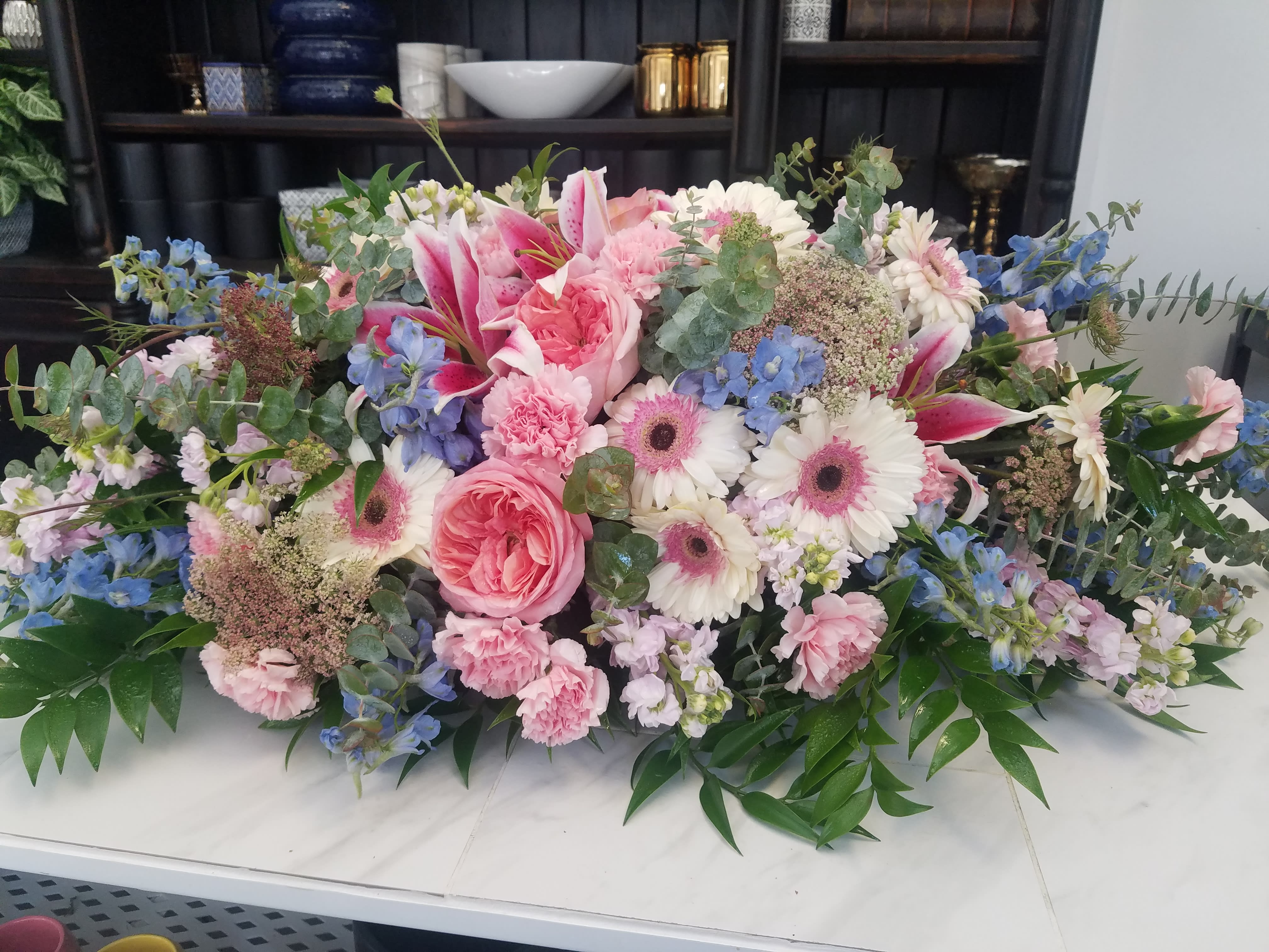 Large pastel floral arrangement with pink and white blooms and blue accents