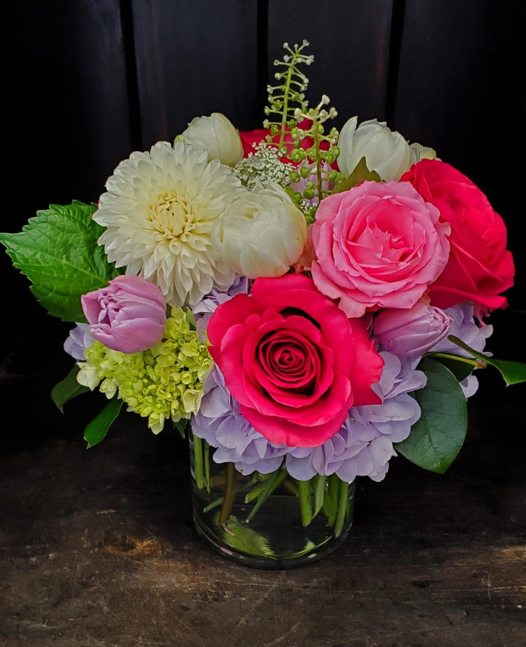 Mixed bouquet of pink, white, and lavender flowers in a glass vase