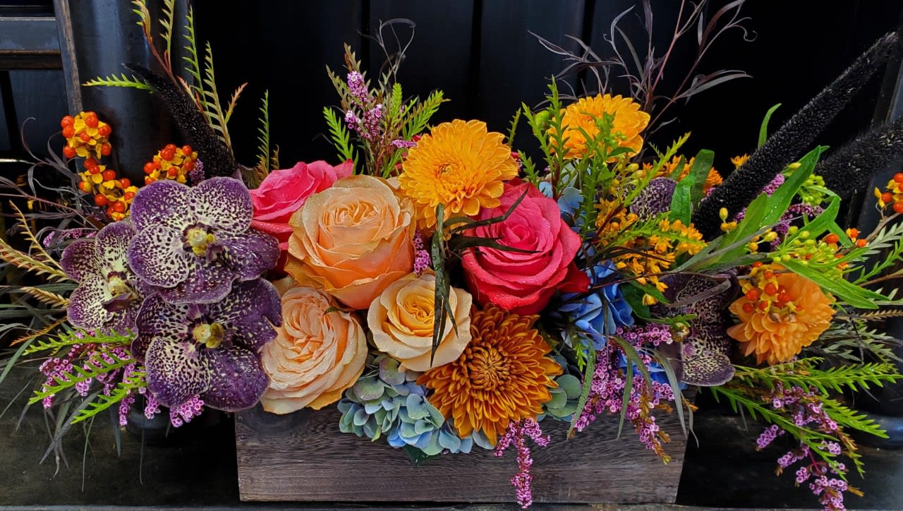 Colorful floral arrangement in a wooden box with roses and orchids