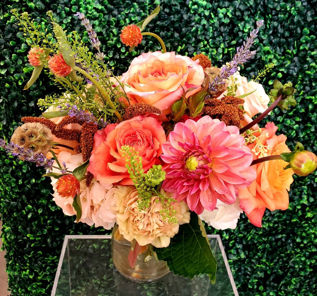 Mixed bouquet of peach, pink, and cream flowers in a clear glass vase