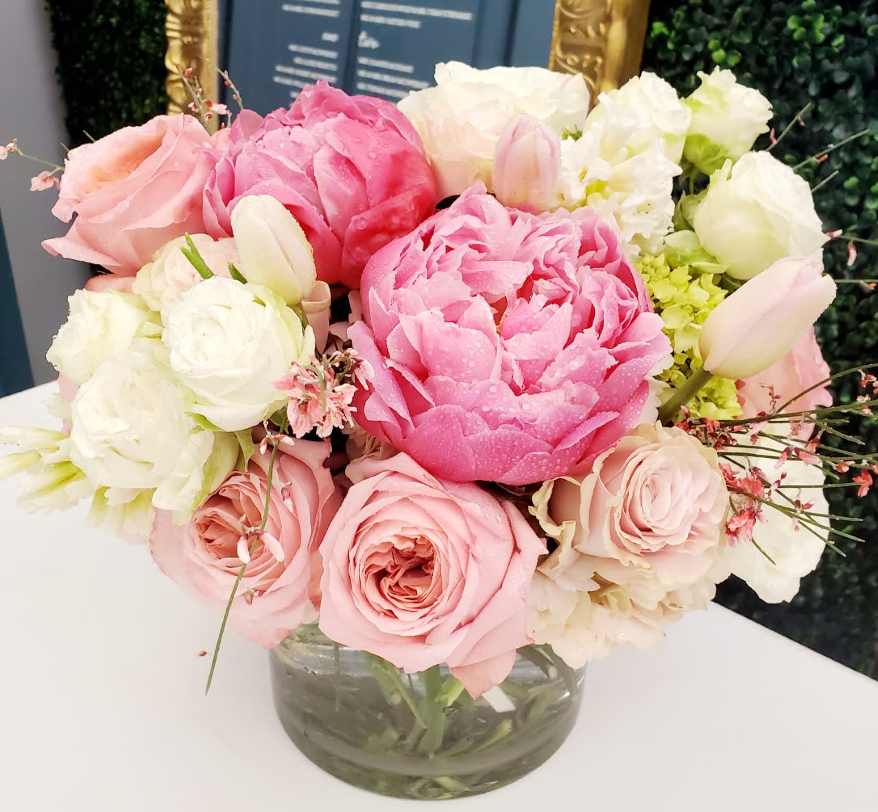 Pink and white bouquet of roses and peonies in a glass vase