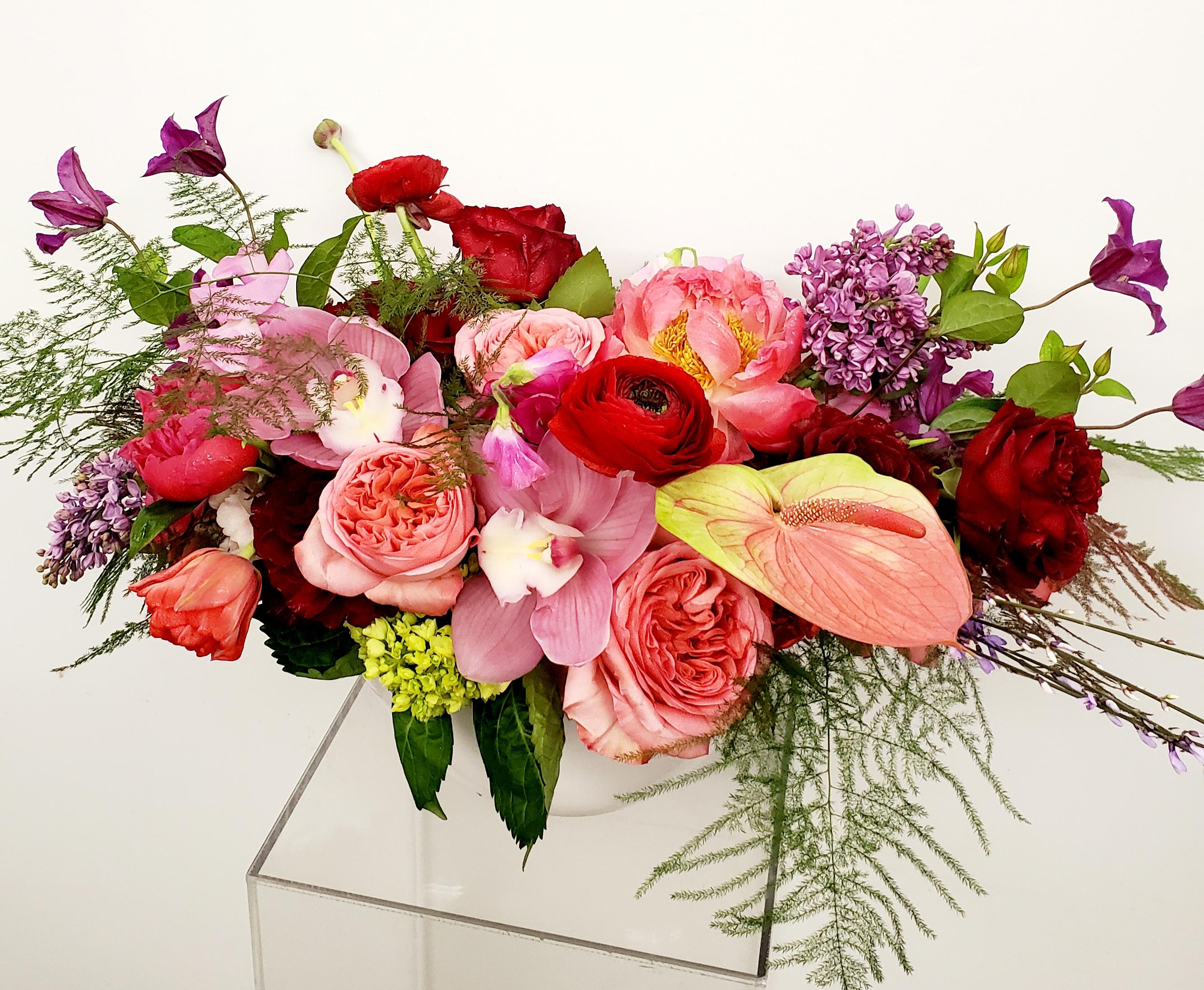 Mixed bouquet of pink, red, and purple flowers in a clear vase