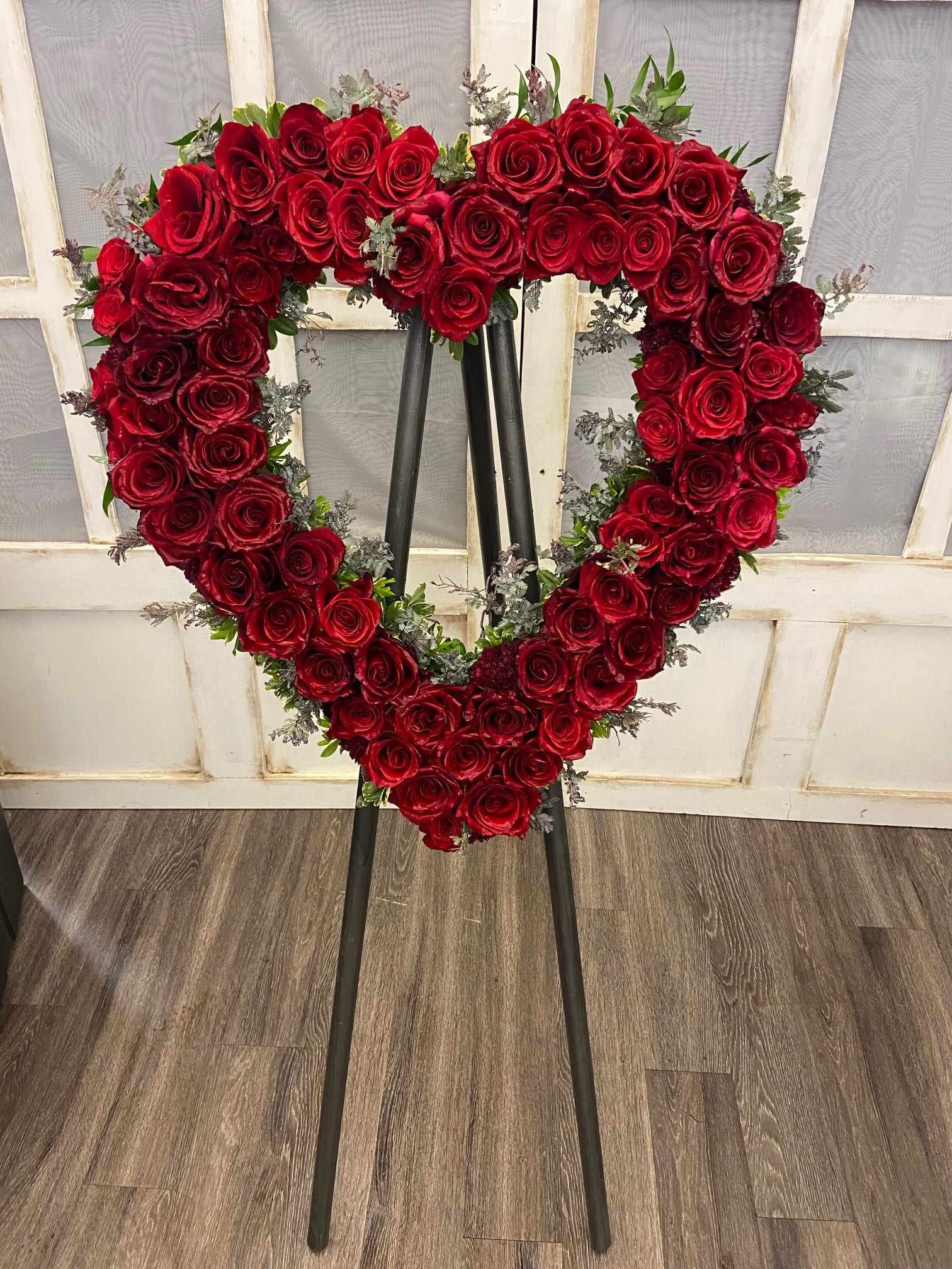 Heart-shaped red rose wreath on a black easel