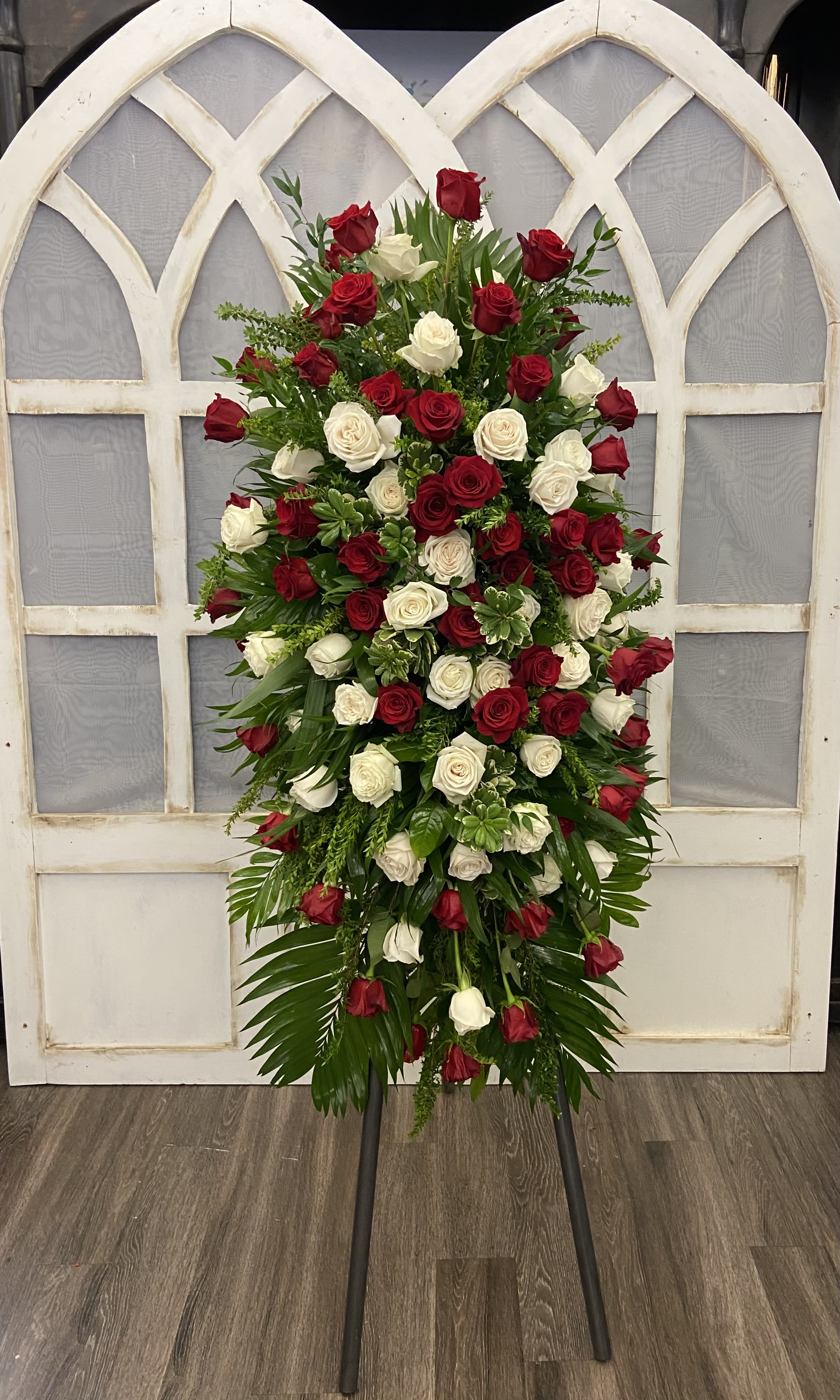 Tall standing arrangement of red and white roses on an easel