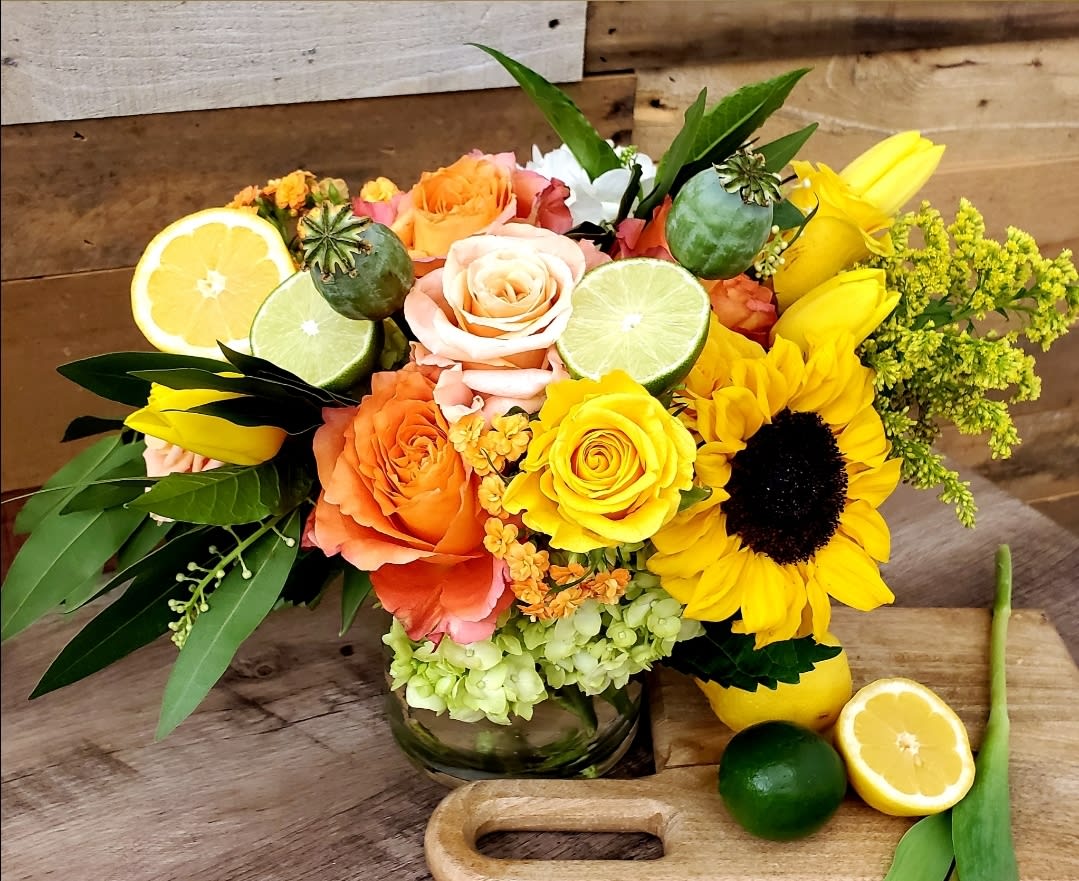 Bouquet of roses and sunflowers with citrus slices in a glass vase