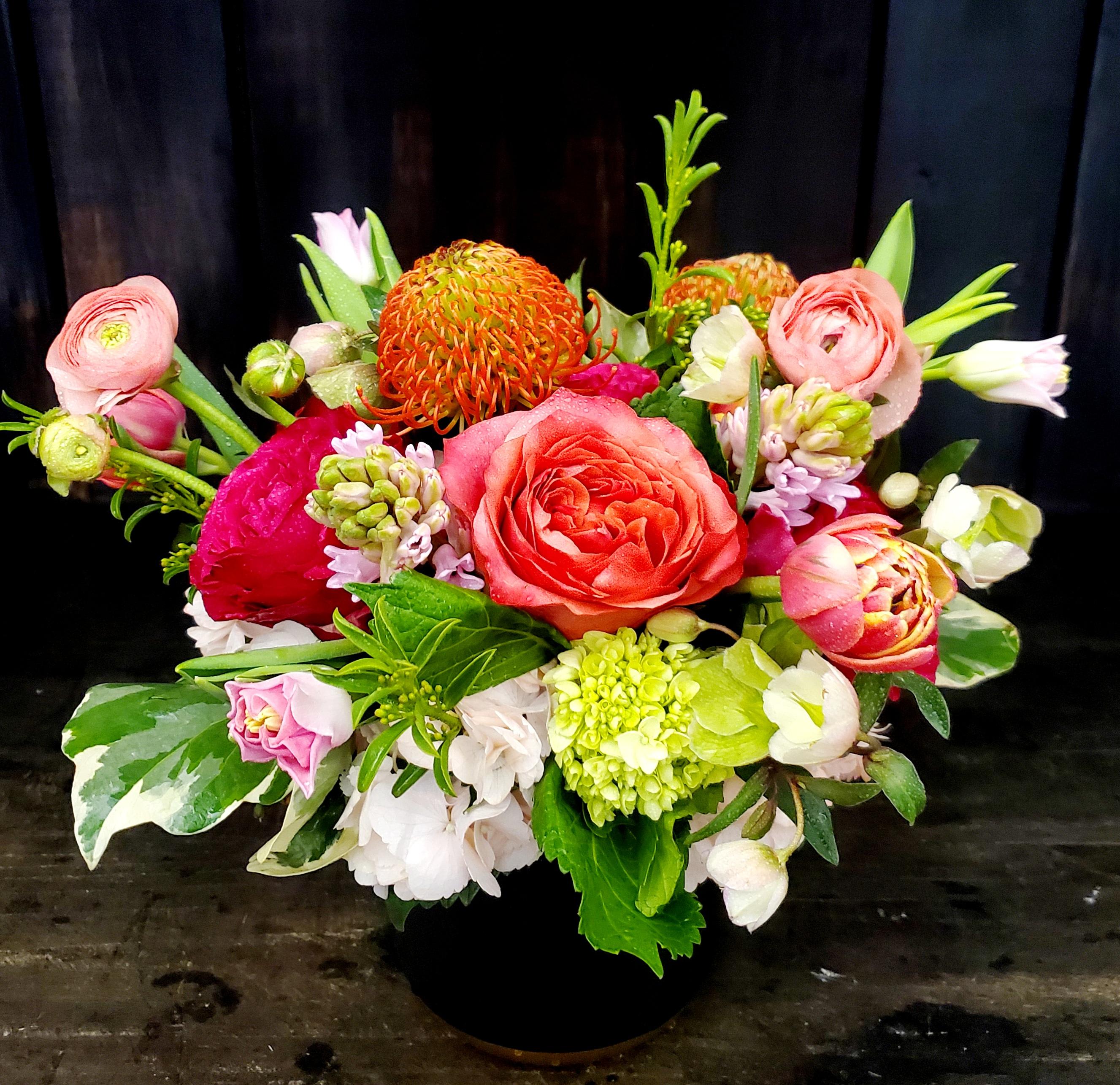 Mixed bouquet in a black vase with pink, orange, and white blooms