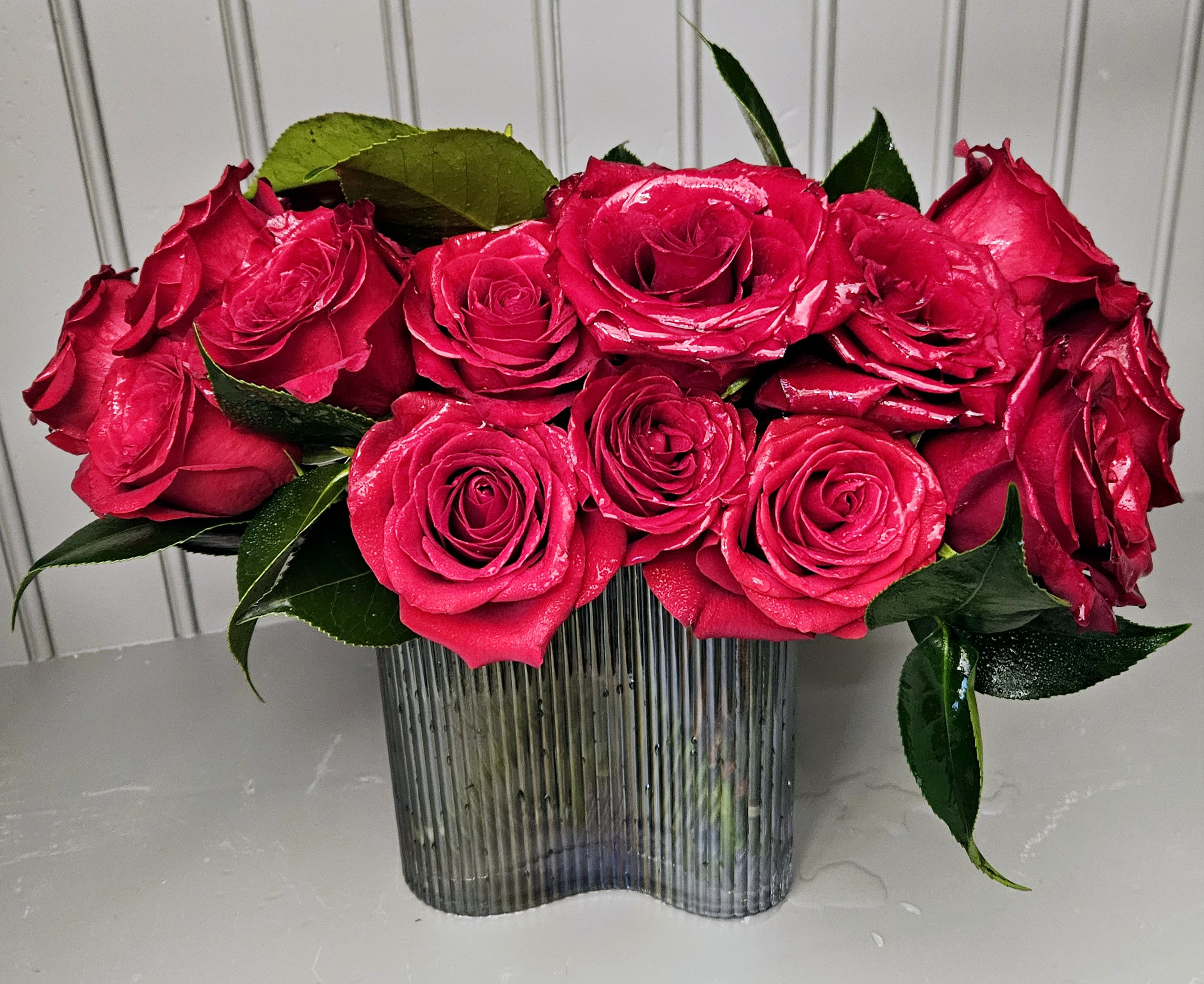 Bright pink roses arranged in a ribbed glass vase