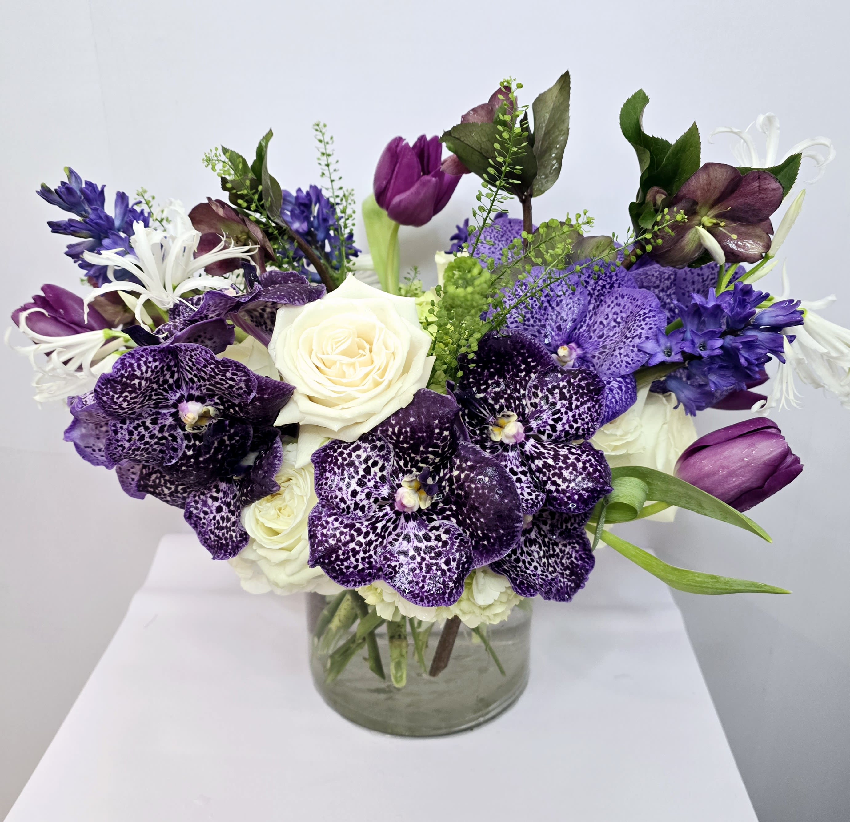 Purple and white floral arrangement in a clear glass vase