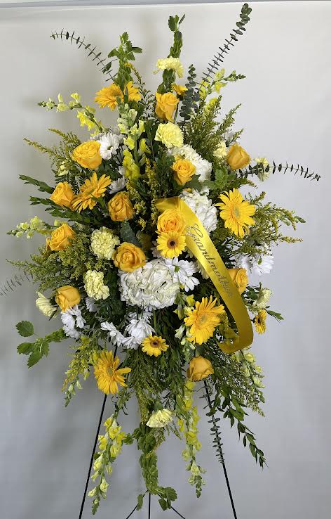 Tall yellow and white sympathy spray on an easel with ribbon