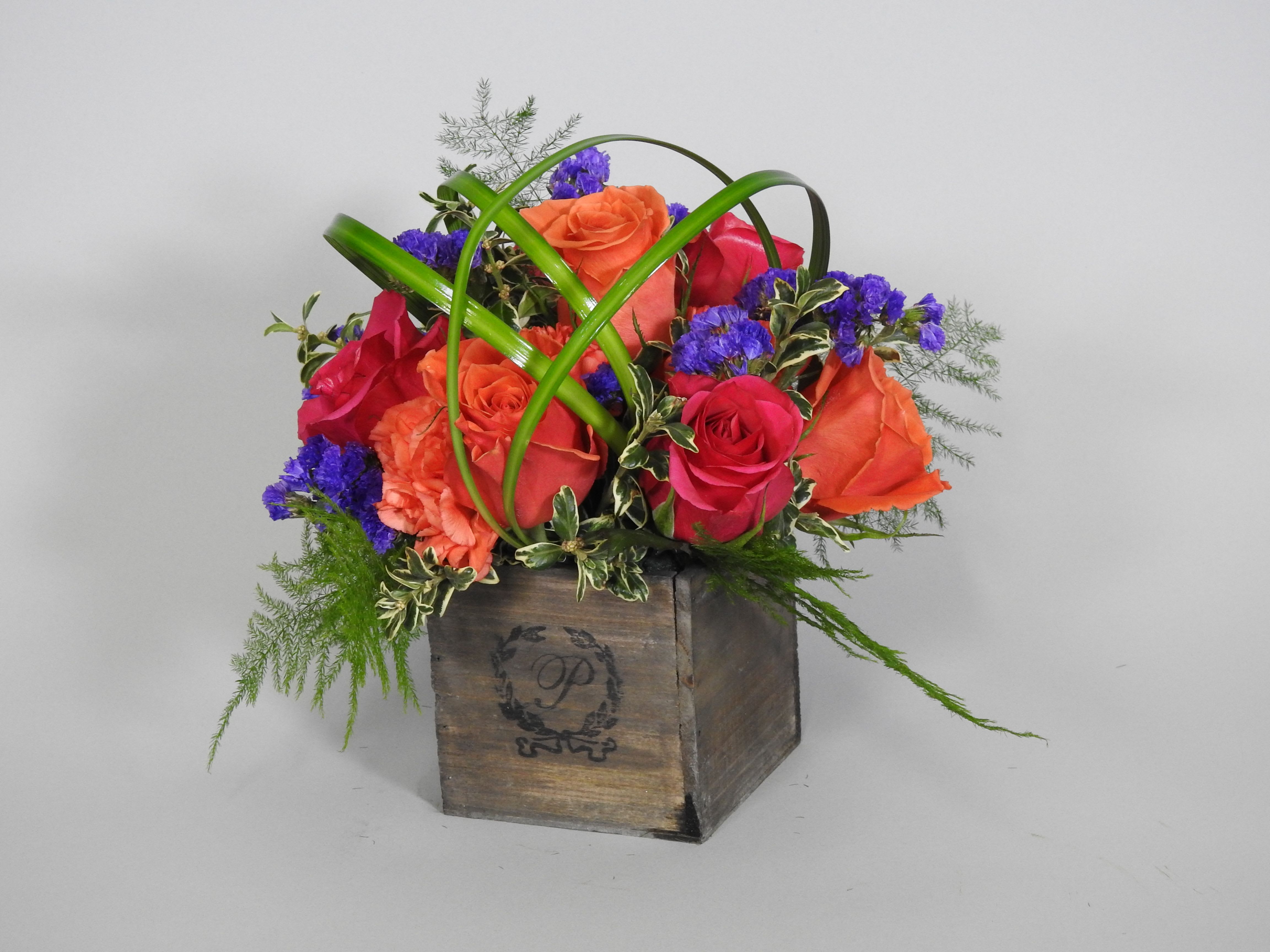 Mixed roses in a wooden box with green decorative loops