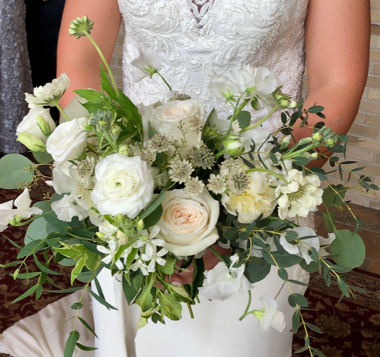 Bridal hand-tied bouquet of white and ivory roses with soft greenery accents.
