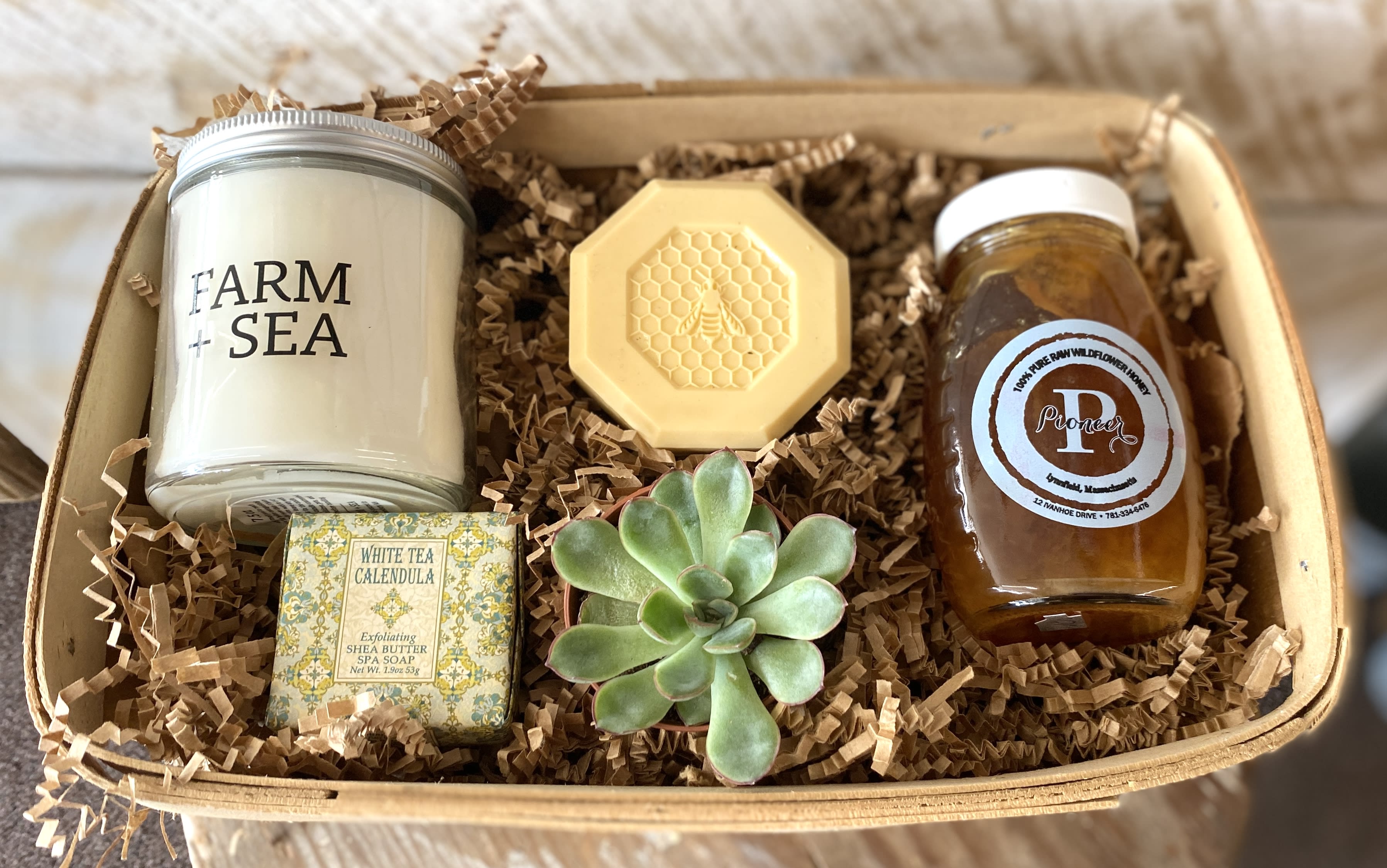 Gift basket with a succulent, candle, soap, honey, and a honeycomb-shaped item