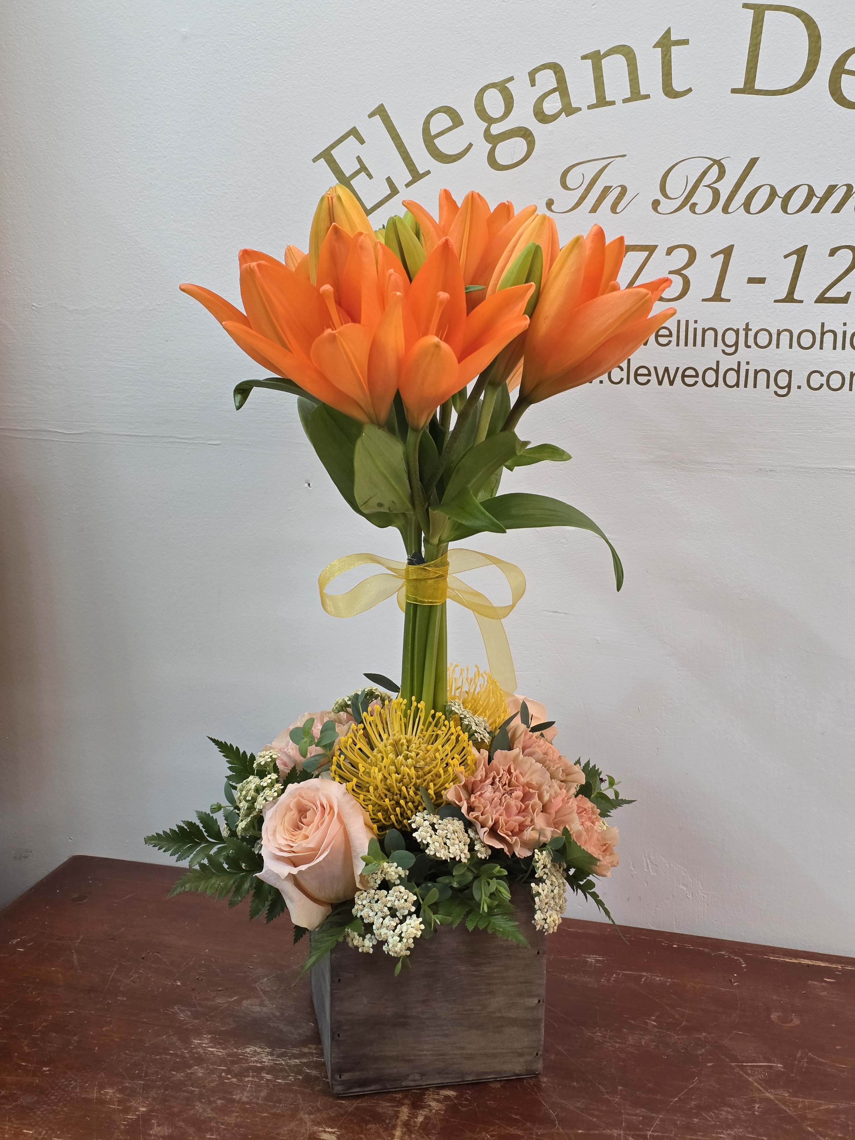 Orange lilies in a wooden box with peach roses and yellow pincushion blooms