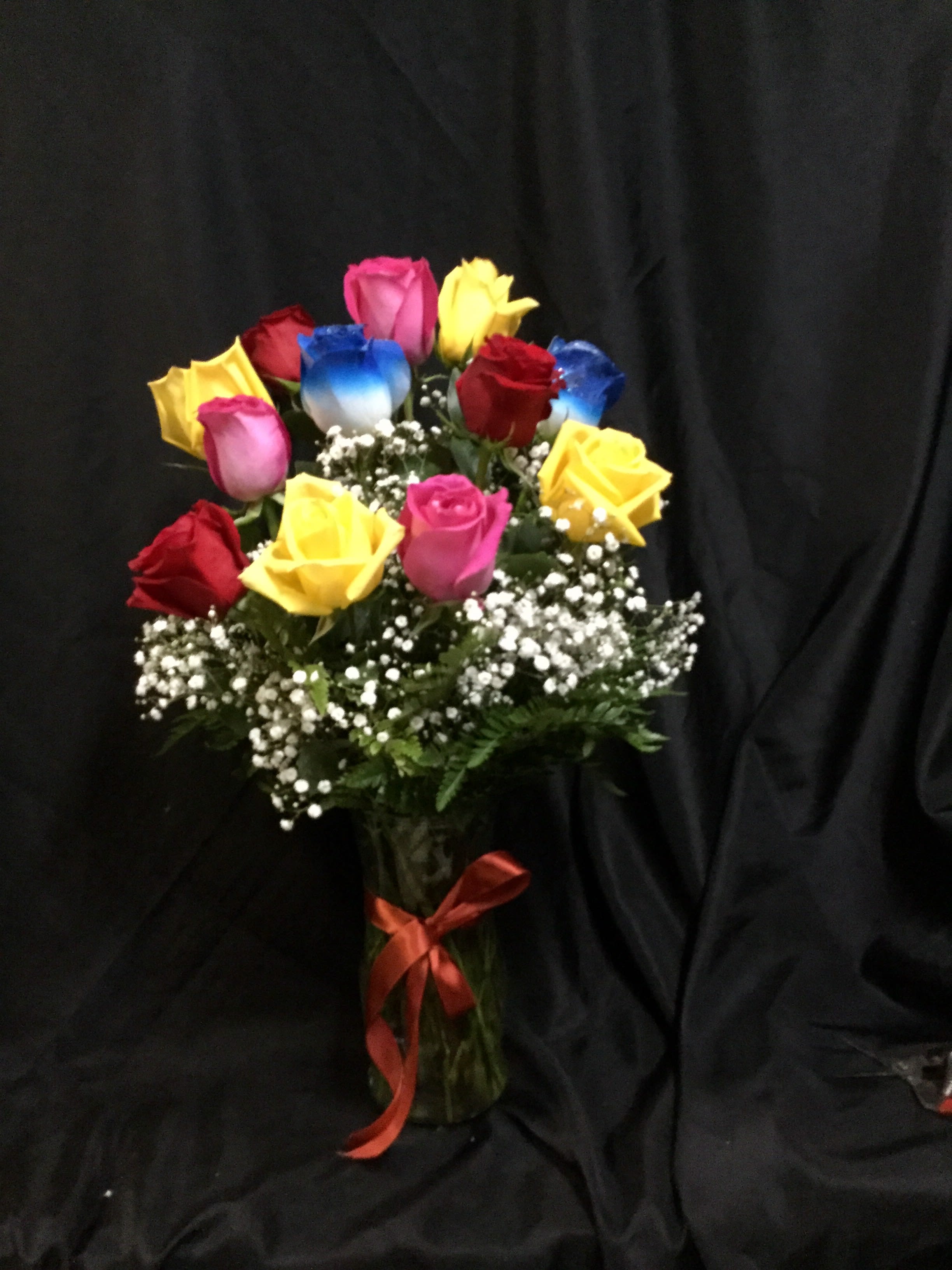 Bouquet of multicolored roses in a glass vase with baby's breath