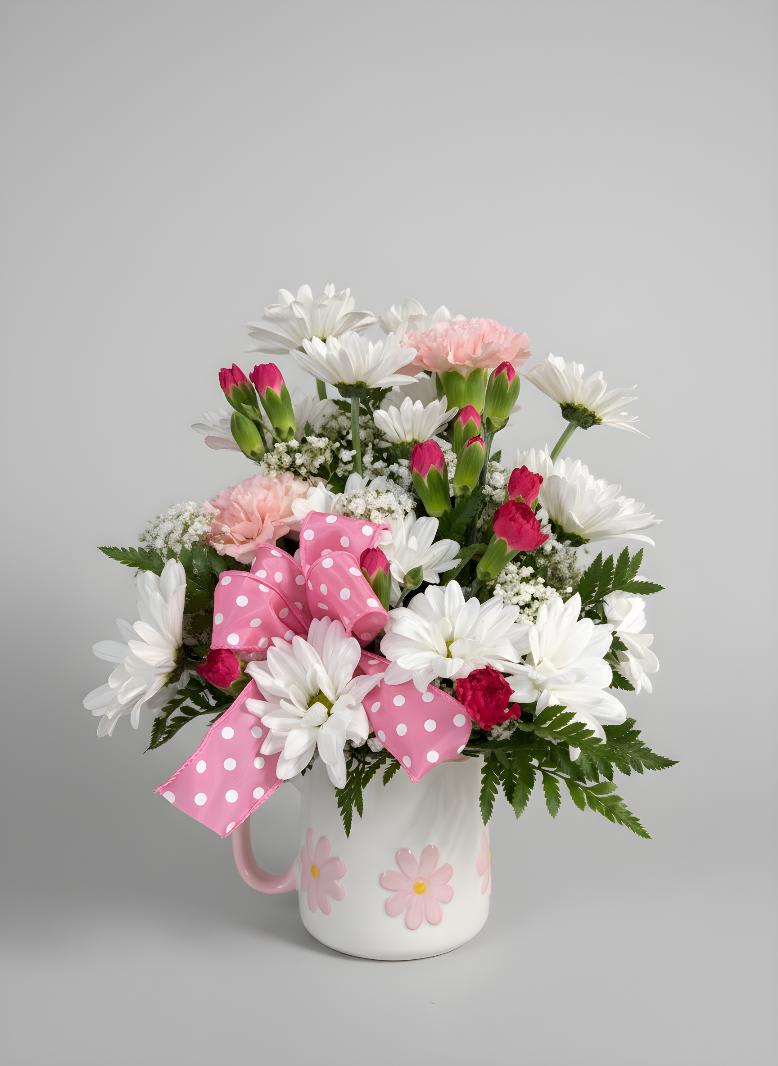 Pink and white flower arrangement in a white mug with a polka-dot bow