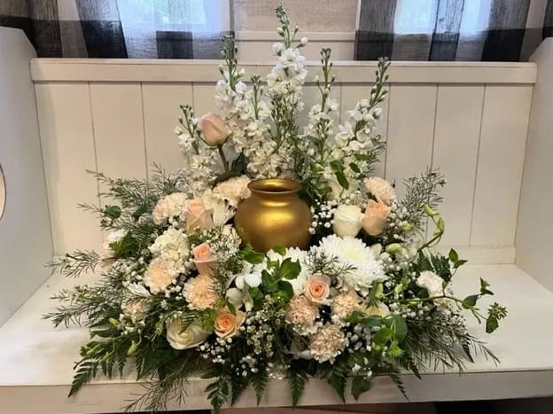 White and blush floral arrangement around a gold urn