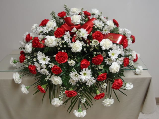 Red and white floral spray with ribbon on a table