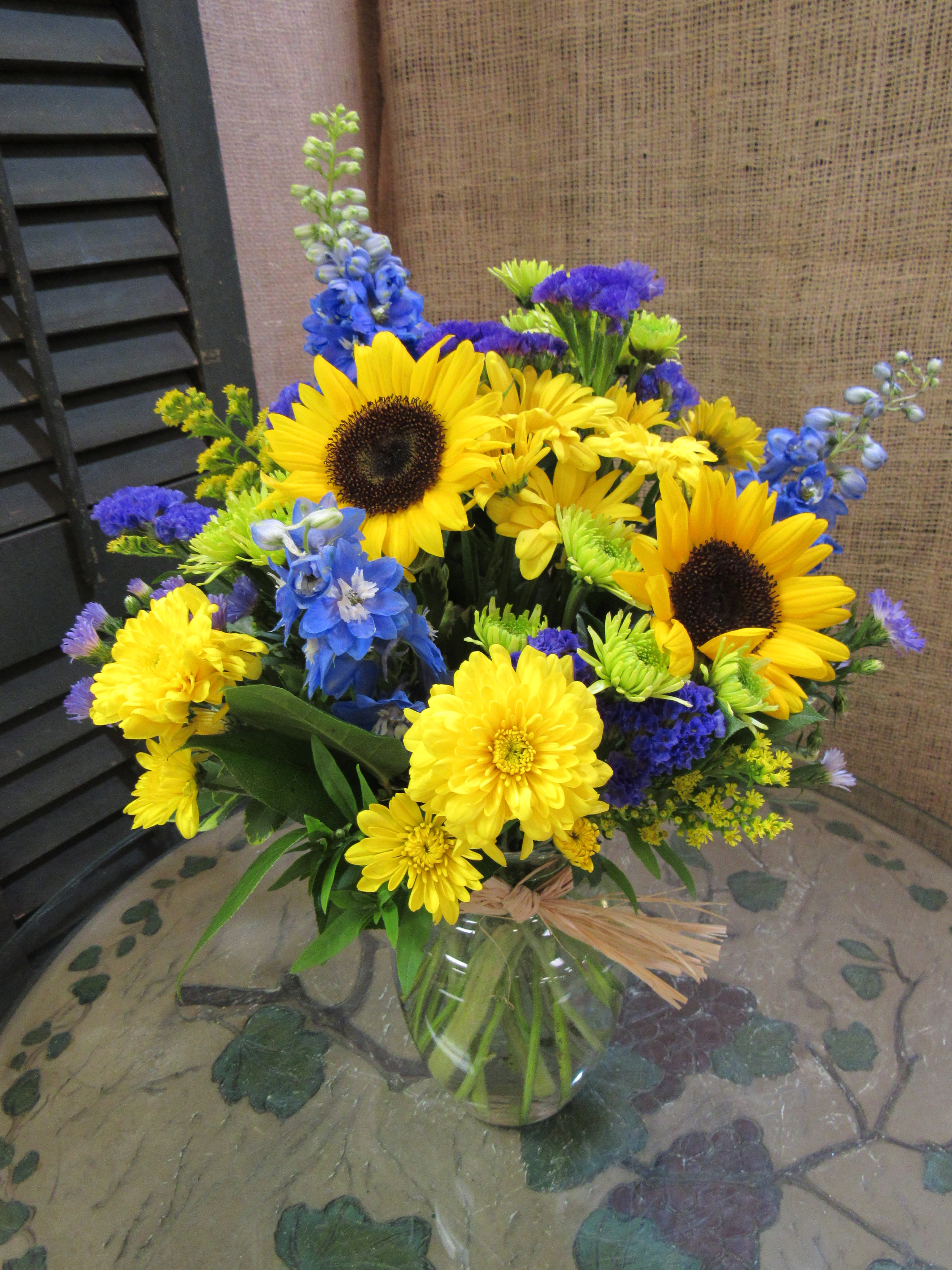Yellow sunflowers and blue flowers in a glass vase
