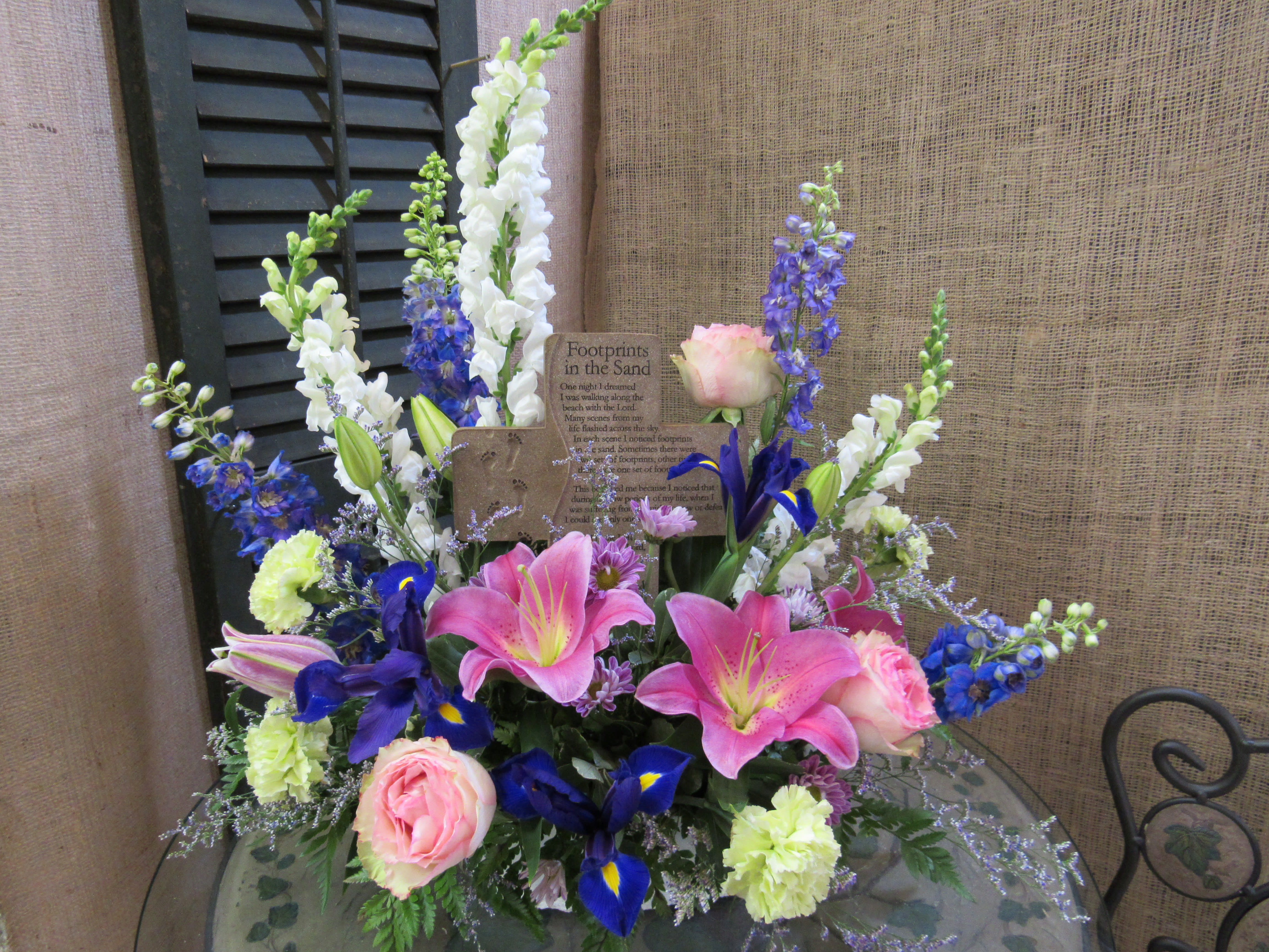 Pink lilies and roses with blue and white flowers in a low arrangement