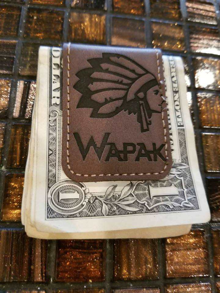 A stack of U.S. dollar bills with a leather WAPAK card holder on top
