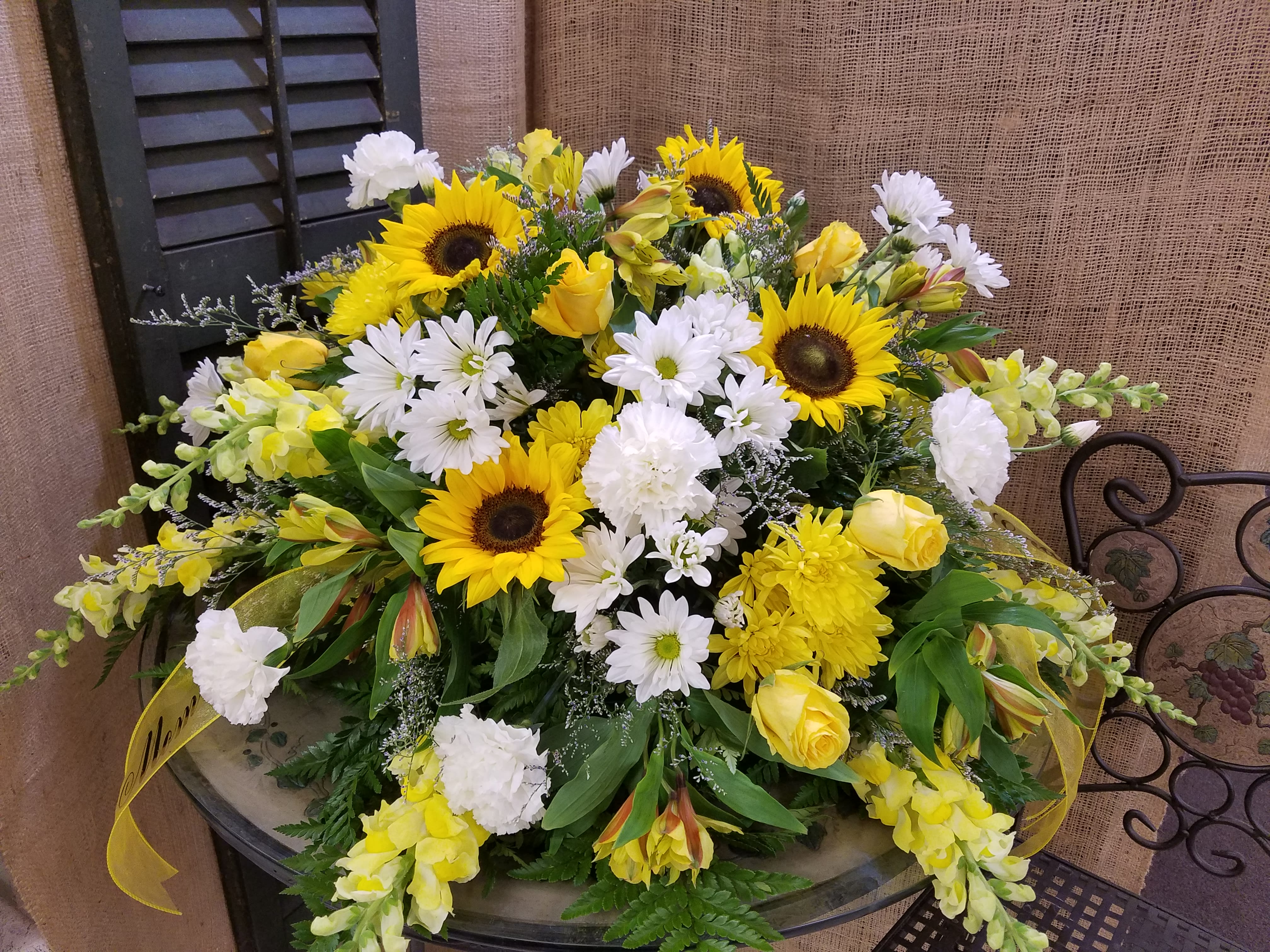 Yellow sunflowers and white daisies arranged with yellow roses in a low bouquet