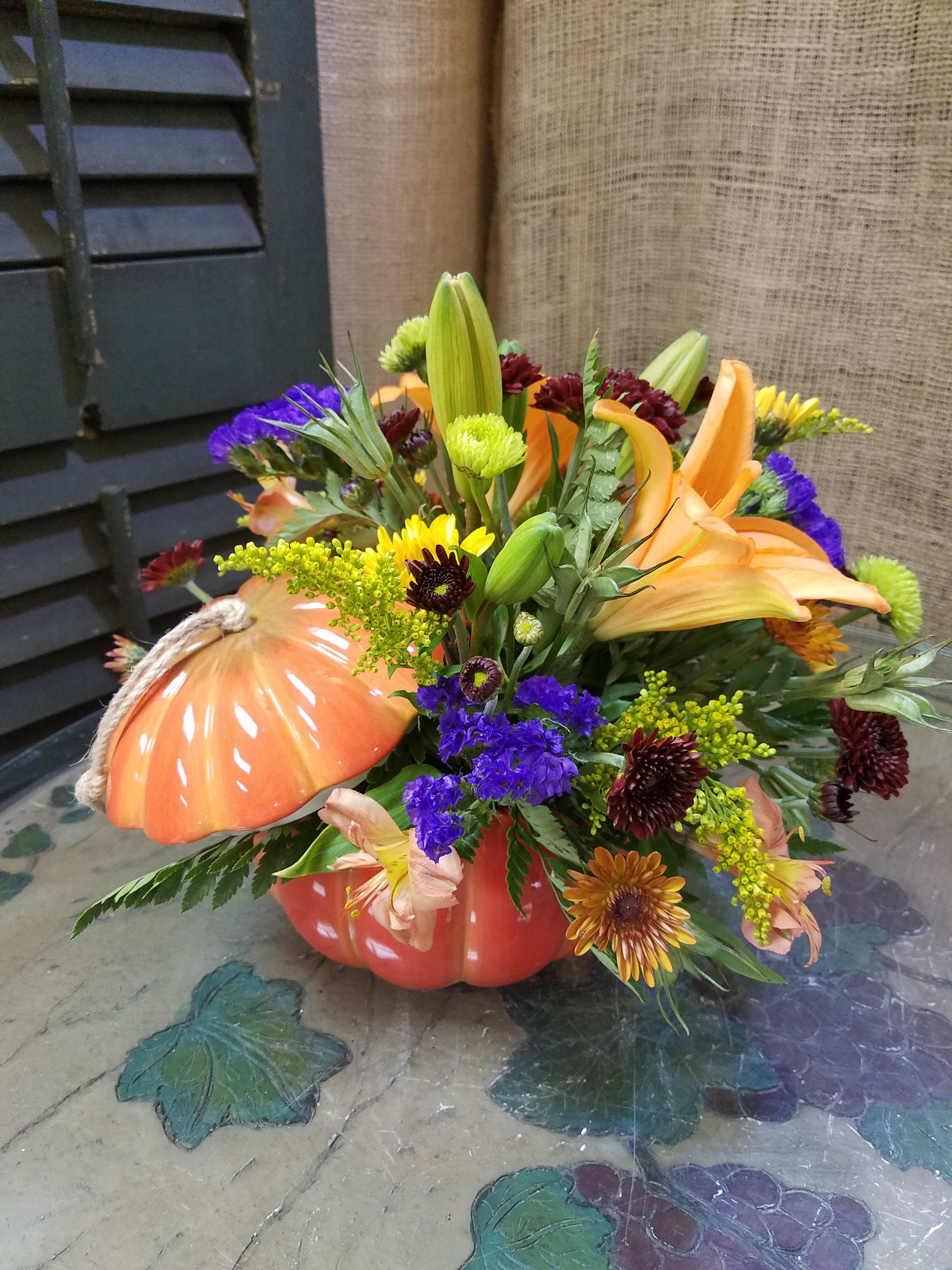 Autumn floral arrangement in a pumpkin-shaped container with lilies and chrysanthemums