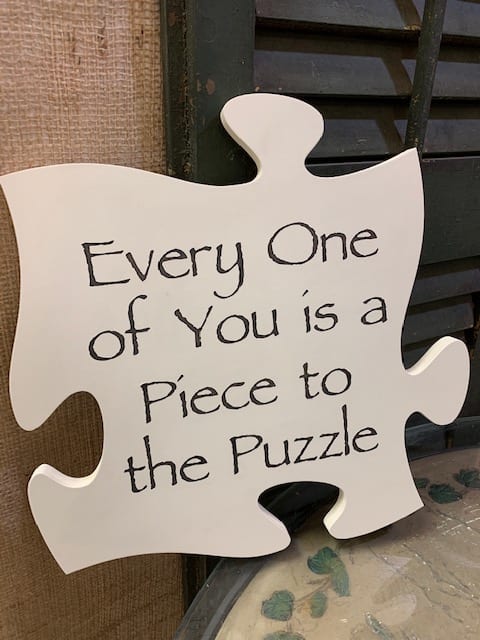 White puzzle-piece sign with handwritten text