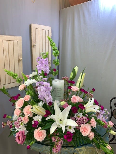 Large floral sympathy arrangement with white lilies, pink roses, and lavender blooms