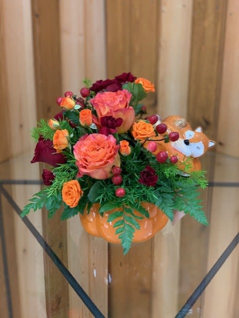 Orange and burgundy rose arrangement in a pumpkin-shaped container