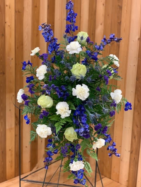 Tall blue and white floral standing spray on a metal easel