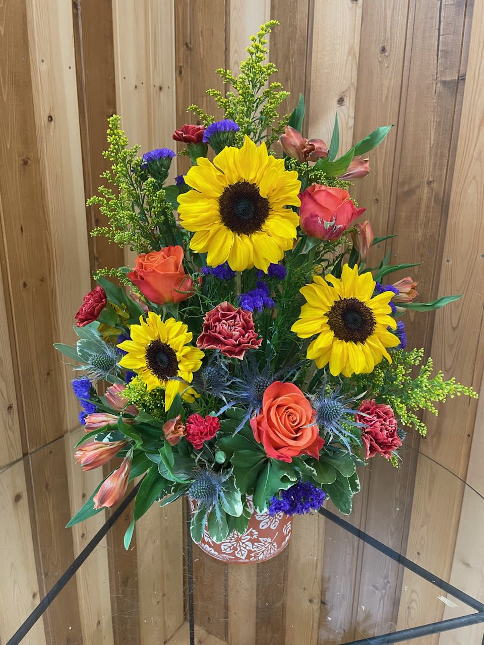 Tall mixed bouquet with sunflowers, roses, and carnations in a decorative vase