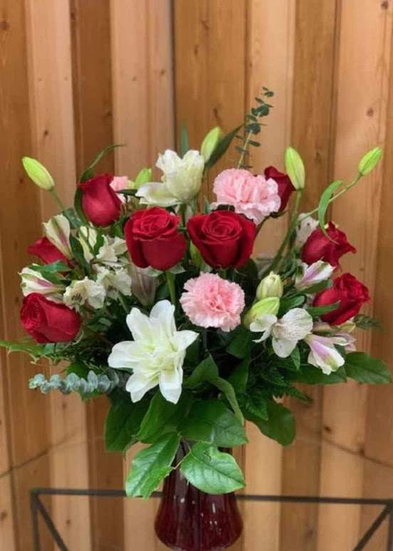 Bouquet of red roses, white lilies, and pink carnations in a red vase