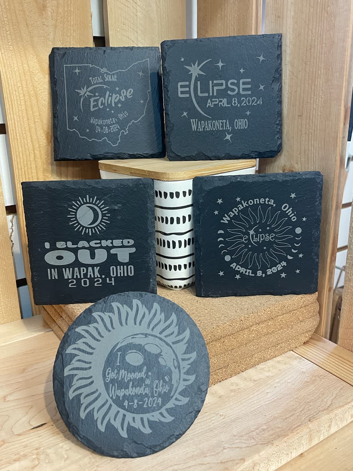 Decorative slate coasters with eclipse-themed designs and a small patterned container