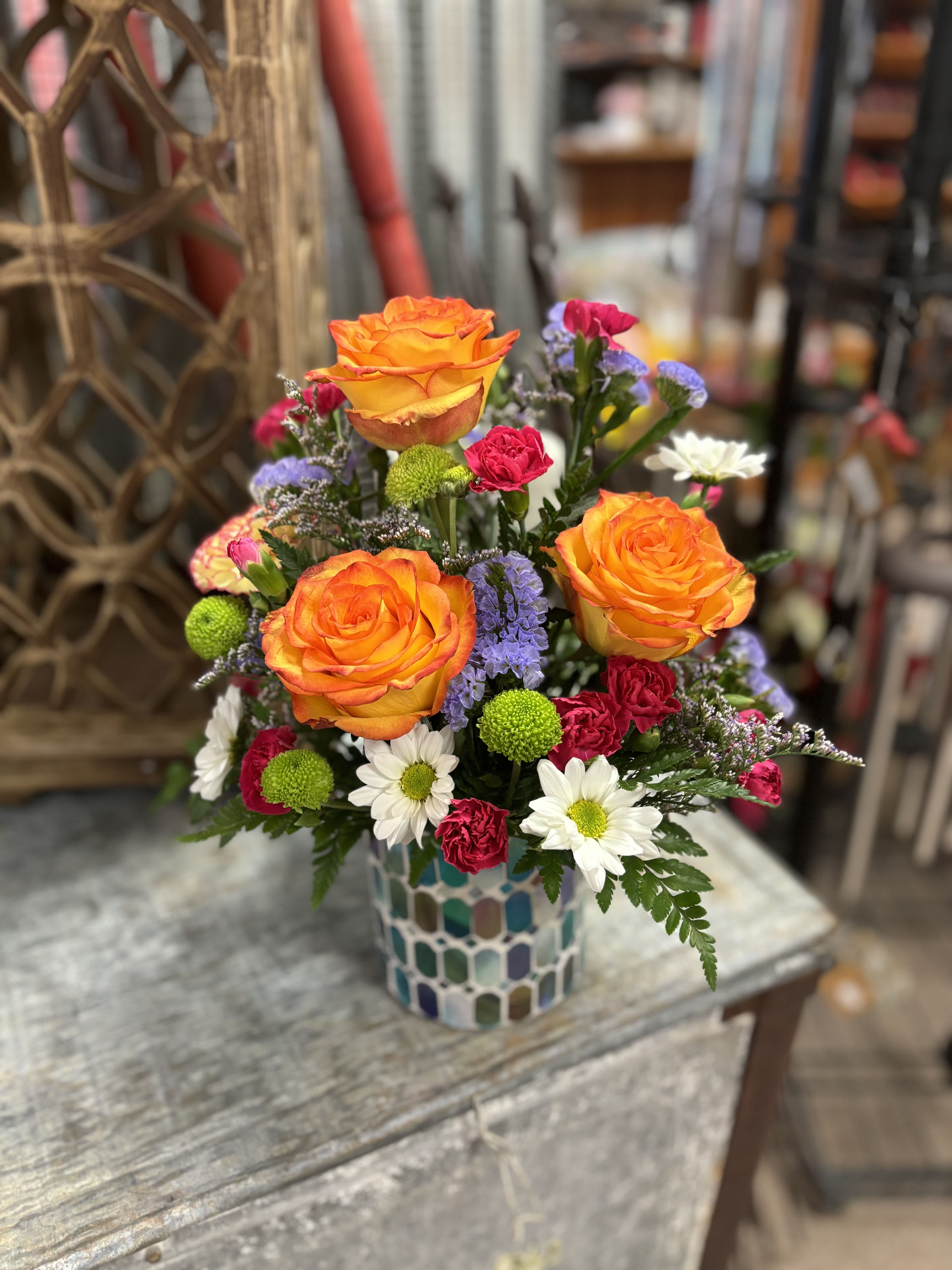 Bright mixed bouquet with orange roses in a mosaic vase