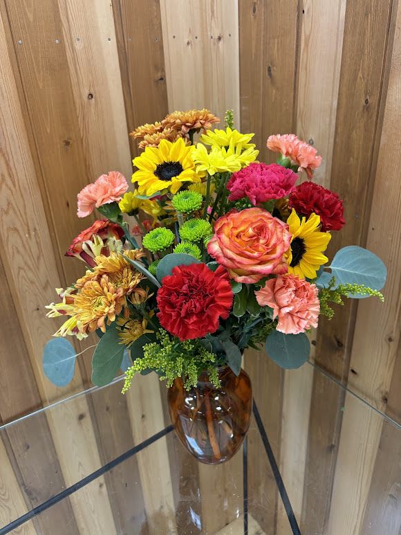 Mixed bouquet of bright flowers in an amber glass vase