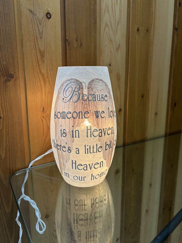 Lit memorial candle with sympathy text on a glass holder
