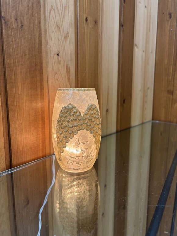 Lit memorial candle with angel wings and a sympathy message