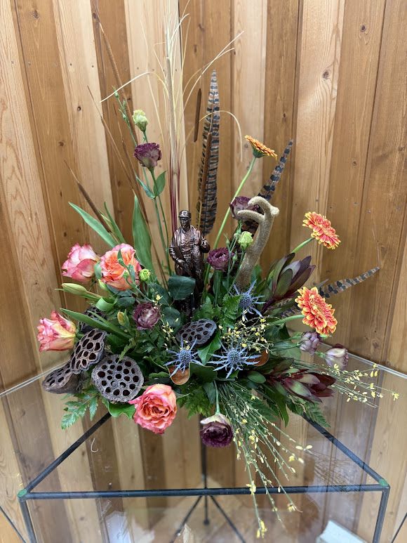 Mixed floral arrangement with orange and purple blooms in a glass vase