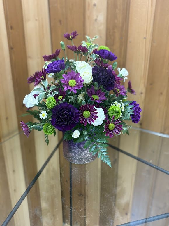 Purple and white flower arrangement in a glittery vase