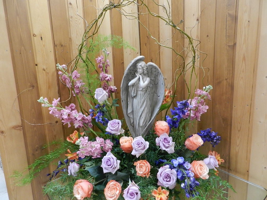 Floral arrangement with a gray angel statue and pastel roses