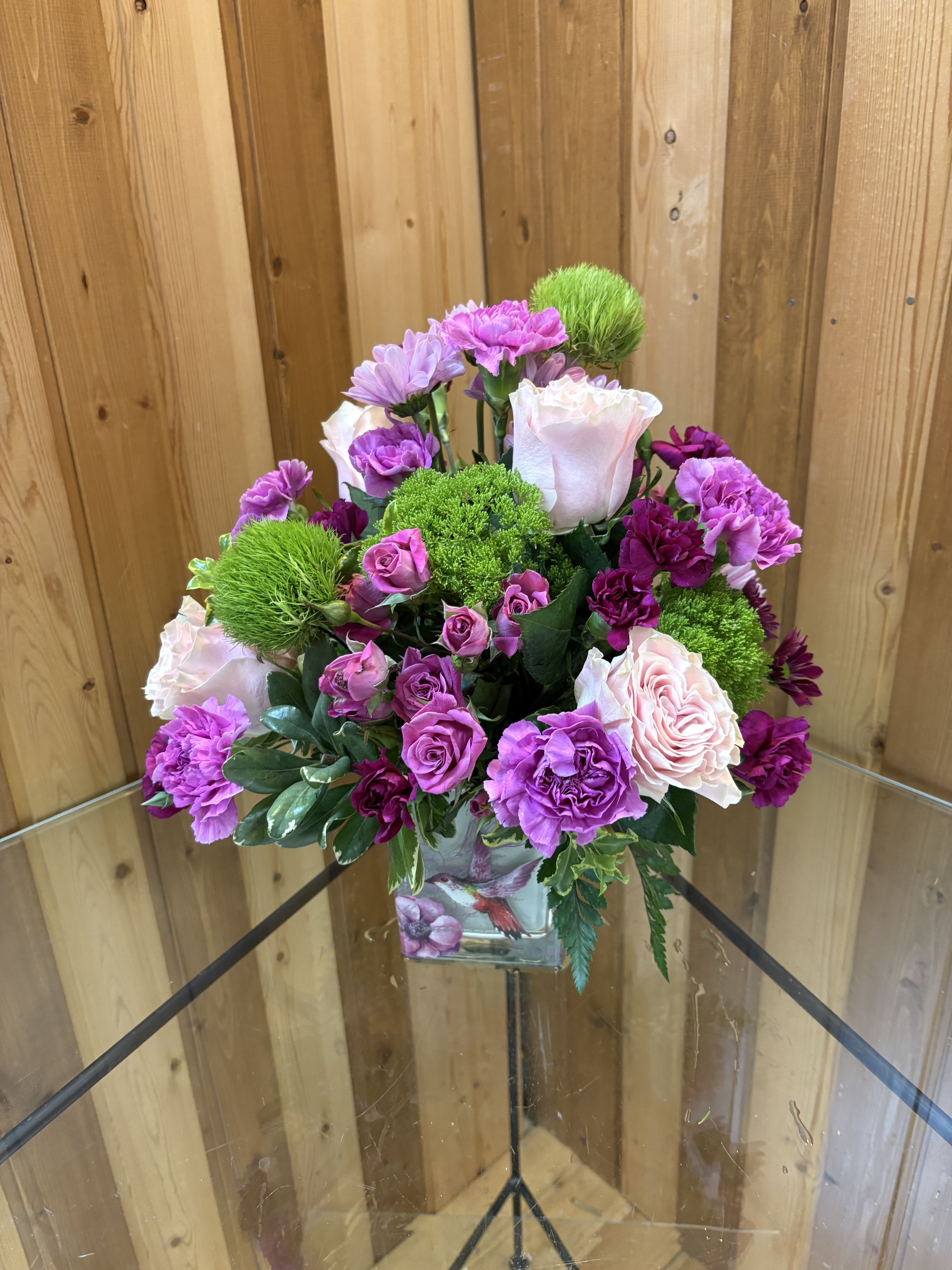 Pink and purple flower arrangement in a square glass vase