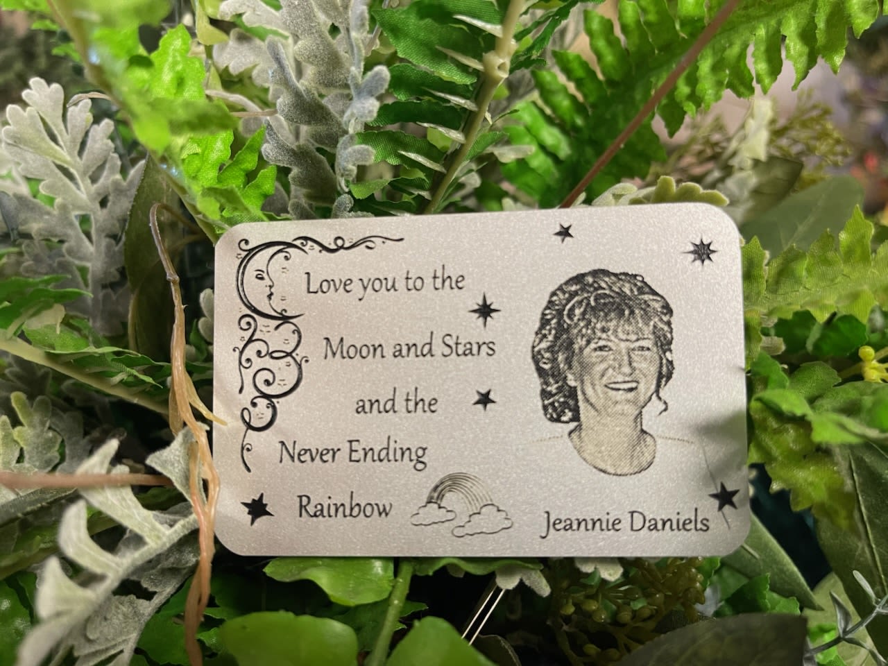 Artificial greenery with a memorial card reading "Love you to the Moon and Stars"