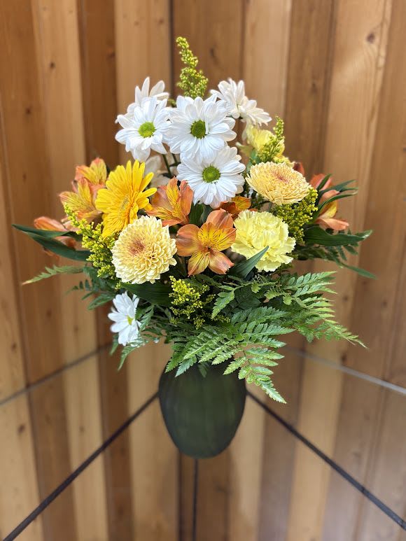 Bouquet of white daisies and yellow-orange flowers in a dark vase
